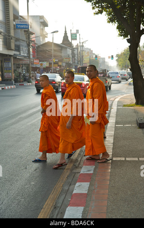Three Buddhist monks crossing the road early evening in Chiang Mai Northern Thailand Stock Photo