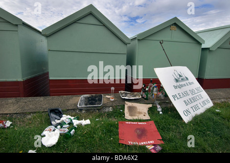 Mess and rubbish by beach huts on Hove lawns, next to a notice asking people not to  barbecue on the lawns. Stock Photo