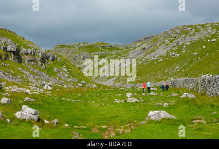 Four people walking along Watlowes dry valley, above Malham Cove, Yorkshire Dales National Park, North Yorkshire, England UK Stock Photo