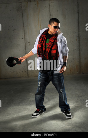 African American hip hop dancer holding hat performing in industrial environment Stock Photo