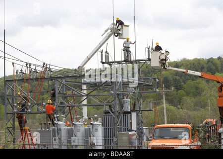 Utility workmen installing updated components to a city gate electrical substation Stock Photo