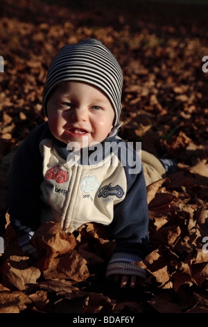 Model released image of less than one-year-old child laughing as he crawls through autumnal leaves