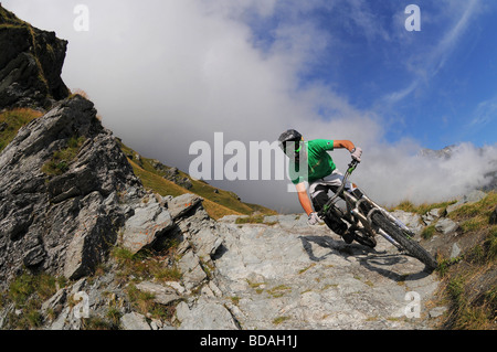 A mountain biker descends a rocky trail on the side of a valley in Les Arcs in the French Alps Stock Photo