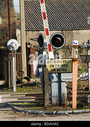 Railroad crossing  with a French warning  sign meaning a train can hid another one Stock Photo
