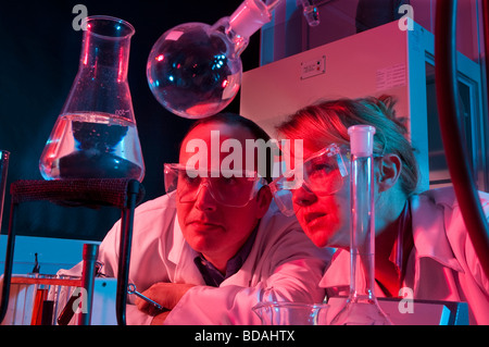 Woman and man in lab coats with lab equipment red and blue light Stock Photo