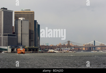 Staten Island Ferry pulls into ferry terminal, Brooklyn and Manhattan bridges in view, lower Manhattan, New York City Stock Photo