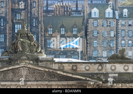 Stone carving of Queen Victoria on top of the Scottish National Gallery in Edinburgh flanked by flags Stock Photo