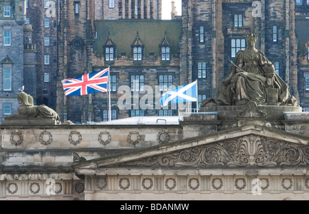 Stone carving of Queen Victoria on top of the Scottish National Gallery in Edinburgh flanked by flags Stock Photo
