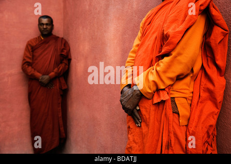 Two monks leaning against a wall, Bodhgaya, Gaya, Bihar, India Stock Photo