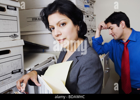 Side profile of a businesswoman searching for files with a businessman standing near her Stock Photo
