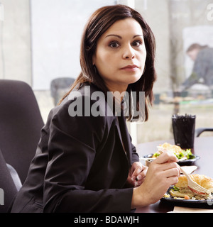 Portrait of a businesswoman eating food in an office Stock Photo