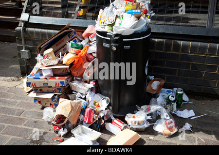 Litter overflows a bin at Camden in North London. Rubbish due to crowds builds throughout the day. A trash mountain grows. Stock Photo