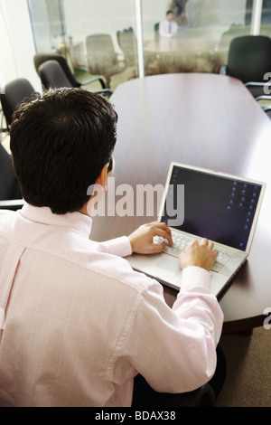 Rear view of a businessman using a laptop in a conference room Stock Photo