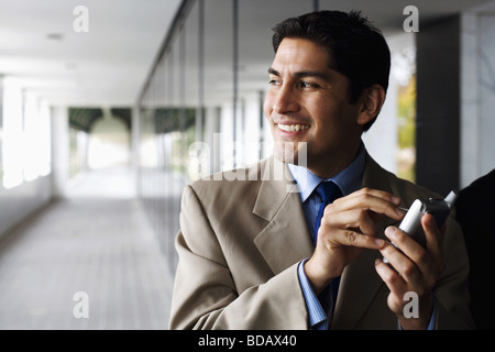 Businessman text messaging on a palmtop and smiling Stock Photo