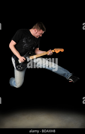 Guitar player jumping over a dark background Stock Photo