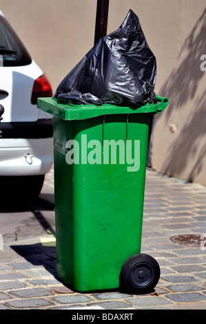 Green wheelie bin / wheely-bin on pavement of residential street in ...