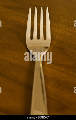 A single fork on a wooden table Stock Photo