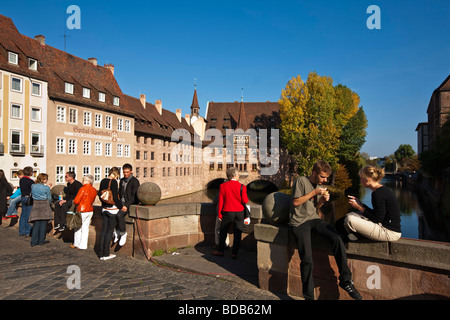 Old City Center of Nuernberg Heilig Geist Spital bridge over the river Pregnitz people Nuernberg Germany Stock Photo