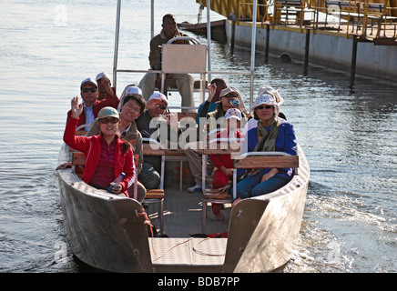 Mostly Asian tourists arriving by boat over the 400m Zambezi River crossing between Botswana and Kazungula in Zambia. Stock Photo