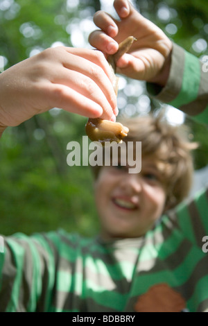 nine year old boy holding up a giant Banana Slug in amazement, rainforest, Vashon Island, Washington state. Stock Photo