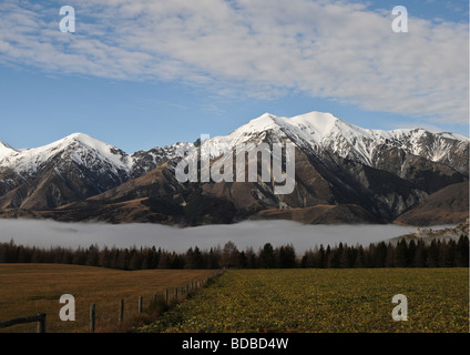 Outstanding view of spectacular snow-capped mountain range and clouds settled in valley of Southern Alps in Arthur's Pass of NZ. Stock Photo