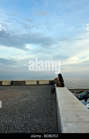 Young Man sitting on a wall new seafront of Pozzuoli Naples Campania Italy Stock Photo