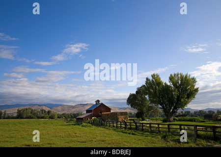 An old red barn and haystack on a ranch near Halfway Oregon on the slopes of the Wallowa Mountains in eastern Oregon Stock Photo