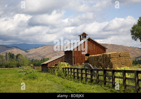 An old red barn and haystack on a ranch near Halfway Oregon on the slopes of the Wallowa Mountains in eastern Oregon Stock Photo