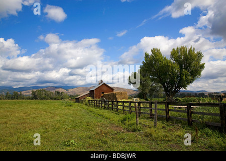 An old red barn and haystack on a ranch near Halfway Oregon on the slopes of the Wallowa Mountains in eastern Oregon Stock Photo