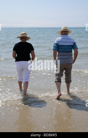 Elderly man and woman walking in the sea at Bognor Regis west Sussex southern England UK Stock Photo