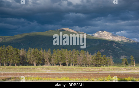 Mountain top lit by sunlight with storm clouds looming Stock Photo