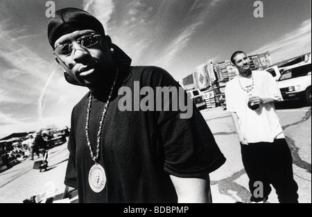 Young African-American man (wearing Tie Down Stocking Cap, shades, and medallion) with young Hispanic friend in background Stock Photo