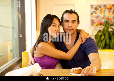 Male Female couple sitting at a table inside a fast food restaurant, looking at camera. Stock Photo