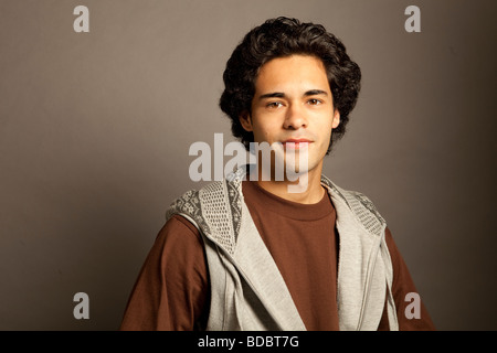 Portrait of Hispanic male with serious expression looking at camera , against gray background. Stock Photo
