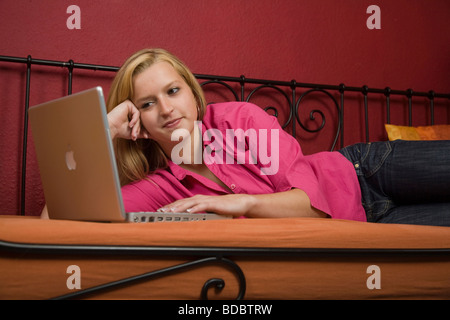 Girl lying on a bed with her laptop Stock Photo