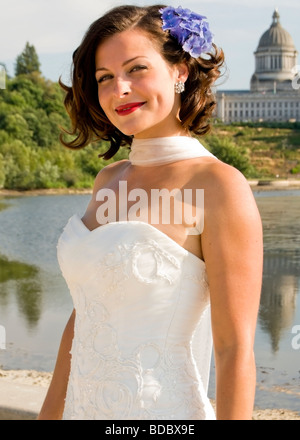 A beautiful bride stands in front of Capitol Lake on a beautiful summer afternoon in Olympia, Washington. Stock Photo