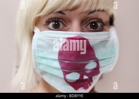 A scared girl  stares into the camera. She wears a customized surgical face mask with a purple red skull printed. Stock Photo