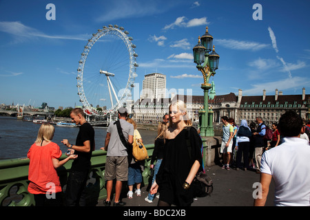 Tourists gather on Westminster Bridge in central London. With the London Eye and other attractions, this is a busy tourism area. Stock Photo