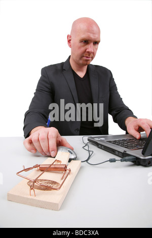 bald headed man using a laptop with mousetrap next computer mouse Stock Photo