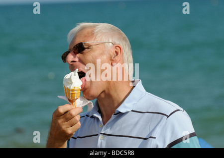 Portrait of an elderly man with grey hair eating an ice cream cornet Stock Photo