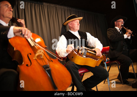 Three middle aged men, Breton folk musicians , playing their instruments one man on the Hurdy Gurdy Stock Photo