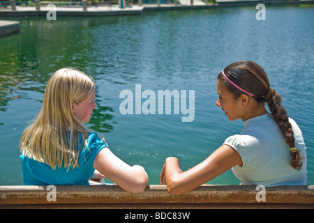 Two Tween tweens girls hang hanging out together Hispanic ethnic diverse multi Tween tweens girls sit park bench converse young person people ©Myrleen Pearson Stock Photo