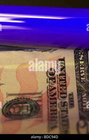 using an ultra violet black light to check a fifty dollar banknote to verify that it is genuine Stock Photo