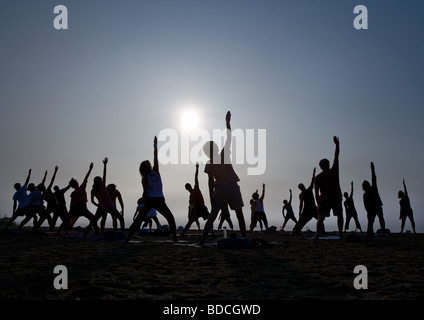 A Yoga Class stretches towards the sky on a beach in Guilford Connecticut USA Stock Photo