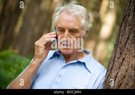 mature man using mobile phone in forest, norfolk, england Stock Photo