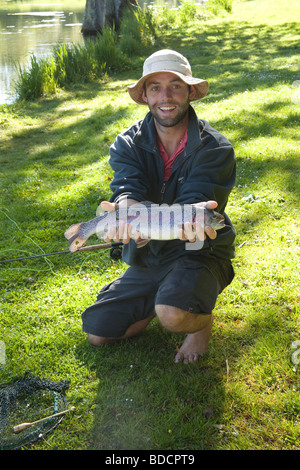 Trout fisherman with a rainbow trout at Meon Springs Trout Fishery, Hampshire , England. Stock Photo