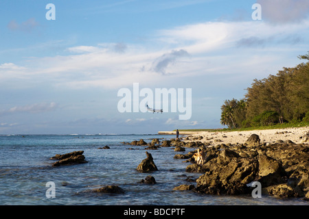 A plane, coming into land,  flying low over a beach on Rarotonga in the Cook Islands Stock Photo