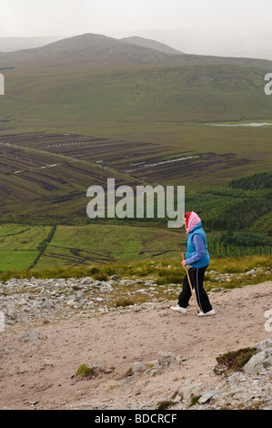 Pilgrim with walking stick descending from the rocky top section of Croagh Patrick on Reek Sunday, 25th July 2009 Stock Photo