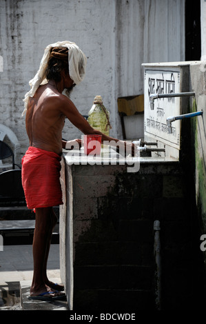 sadhu holy man wash washing cleanse cleansing outdoors tap water Pashupatinath Temple kathmandu nepal Stock Photo