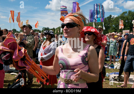 A woman wearing festival clothes surrounded by festival audience dressed in hippie clothing enjoying the show at WOMAD music festival Stock Photo